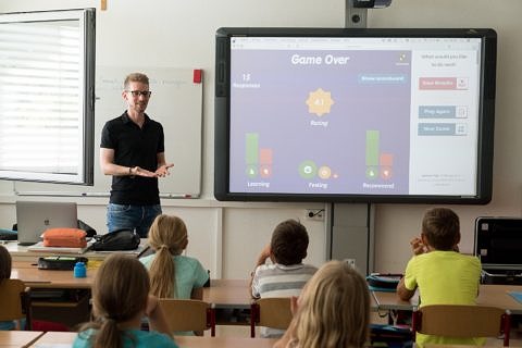 Lehrkraft vor einer Schulklasse an einem Smartboard