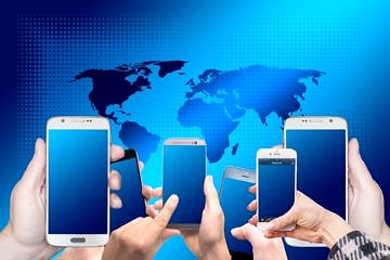 Die Weltkarte in Blautönen, davor viele Hände, Smartphones halten mit blauem Display.